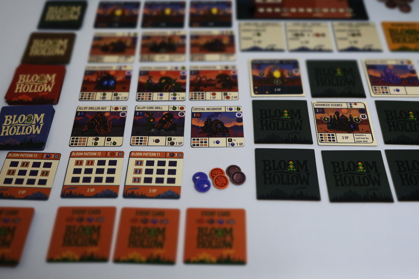 Collection of 'Bloom Hollow' board game cards and pieces on a white surface