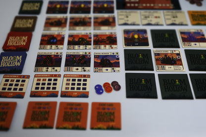 Collection of 'Bloom Hollow' board game cards and pieces on a white surface
